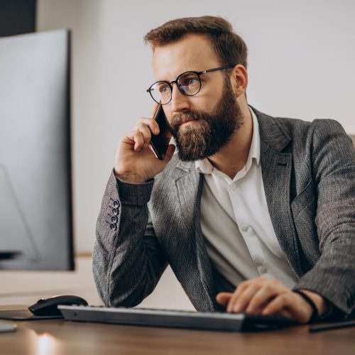 Young business man talking on phone and working on computer